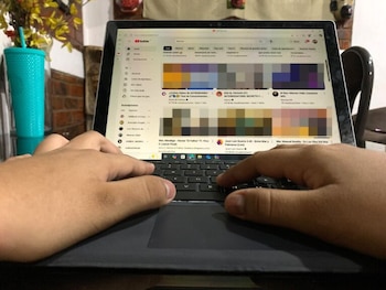 Ilustración de una joven con cabello oscuro sonriendo mientras usa un smartphone, con burbujas de chat, signos de admiración y un emoji sonriente flotando alrededor, sobre un fondo púrpura