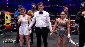 Un árbitro sujeta las manos de dos boxeadoras en un ring. Hay público y una cifra de espectadores con logos de redes sociales en pantalla.