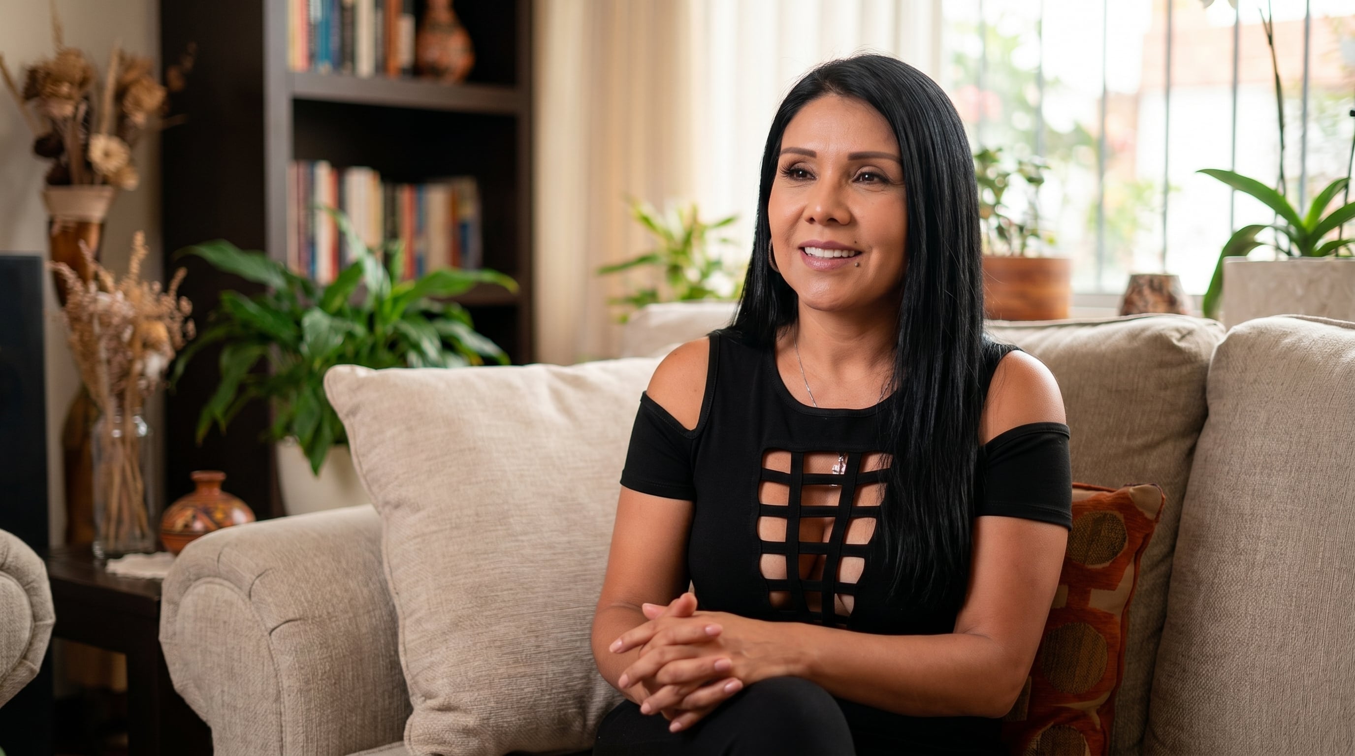 Tula Rodríguez sonríe mientras se sienta en un sofá en su casa, abordando la polémica generada por el informe de Magaly TV y afirmando que
