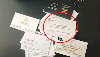 Varias tarjetas de presentación sobre una superficie oscura, con una tarjeta resaltada en un círculo rojo que muestra el nombre de Fernando Cerimedo