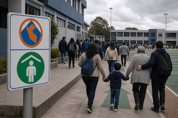 Personas de espaldas caminan por una vereda con flechas verdes junto a un cartel con símbolos de seguridad y el mapa de Perú.