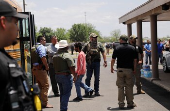 Niños entran en el micro escolar mientras el personal de seguridad hace guardia (REUTERS/Marco Bello)