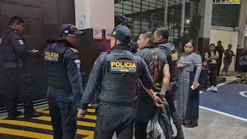 Agentes de uniforme con la inscripción Policía Nacional Civil rodean a un hombre esposado con las manos a la espalda