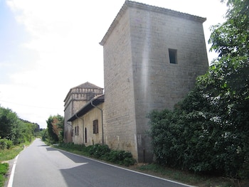 Se aprecia una casa de sillares grandes junto a una carretera.