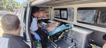 Un socorrista con guantes azules atiende a un hombre recostado en una camilla dentro de una ambulancia