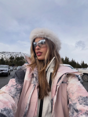 Poggio se fotografió a sí misma con campera rosa y gorra de piel blanca, con las montañas nevadas de fondo