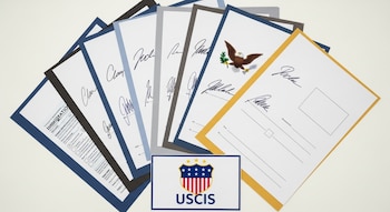 Formularios migratorios genéricos dispuestos en abanico con ejemplos de firmas manuscritas y digitales, y un cartel del logo de USCIS en un escritorio.