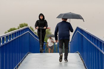 Peatones cruzan un puente sobre
