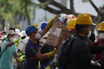 Los rescatistas distribuyen paquetes de alimentos a los equipos de rescate y voluntarios que buscan entre los escombros cuatro días después del terremoto que azotó Colombia - crédito AP Foto/Iván Valencia