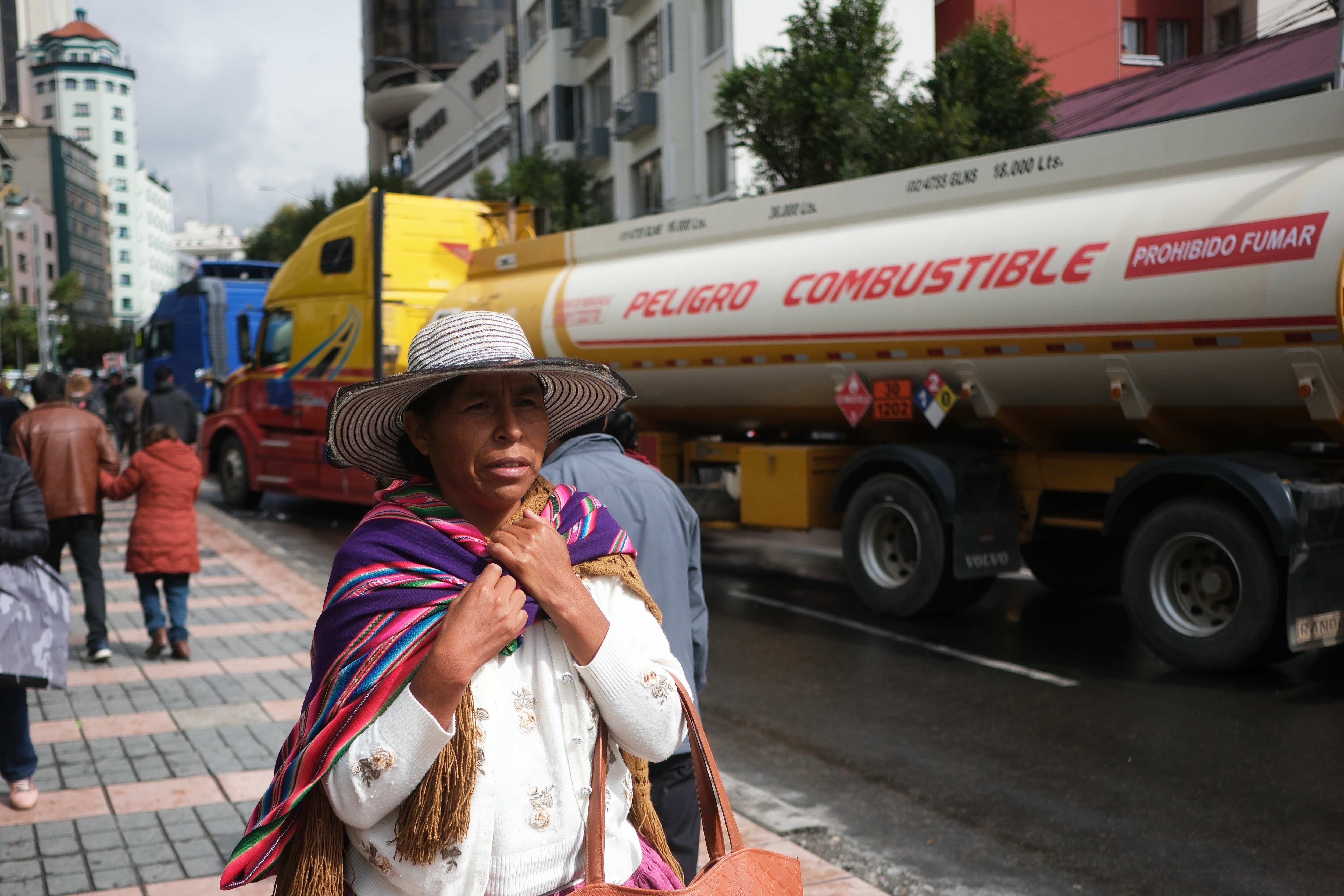 Varias transeúntes fueron registrados este lunes, 19 de febrero, al caminar junto a carrotanques de combustible, durante una protesta del sector transportador, en La Paz (Bolivia). EFE/Luis Gandarillas