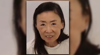 Fotografía en plano medio de una mujer de cabello oscuro y ropa blanca, centrada sobre un fondo difuminado.