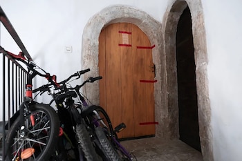 Varias bicicletas aparcadas a la izquierda, una puerta de madera arqueada sellada con varias tiras de cinta adhesiva roja, y otro arco oscuro a la derecha