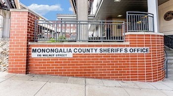 Muro de ladrillo rojo con un letrero que dice Monongalia County Sheriff S Office y una barandilla metálica