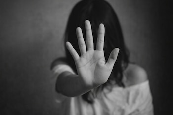 Fotografía en blanco y negro de una persona con la mano derecha extendida hacia adelante, palma abierta, dedos separados. Su rostro está desenfocado.