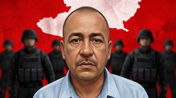 Hombre de bigote en primer plano con camisa celeste. Fondo rojo con silueta del mapa de Michoacán en blanco y figuras armadas con chalecos negros.