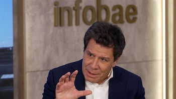 Primer plano de Facundo Manes, un hombre de tez clara con cabello oscuro, vistiendo un saco azul y camisa blanca, gesticulando con la mano derecha. Al fondo se ve el logo de Infobae en letras doradas