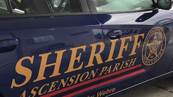 Lateral de un vehículo policial azul oscuro de la Oficina del Sheriff de Ascension Parish con letras doradas y un emblema circular