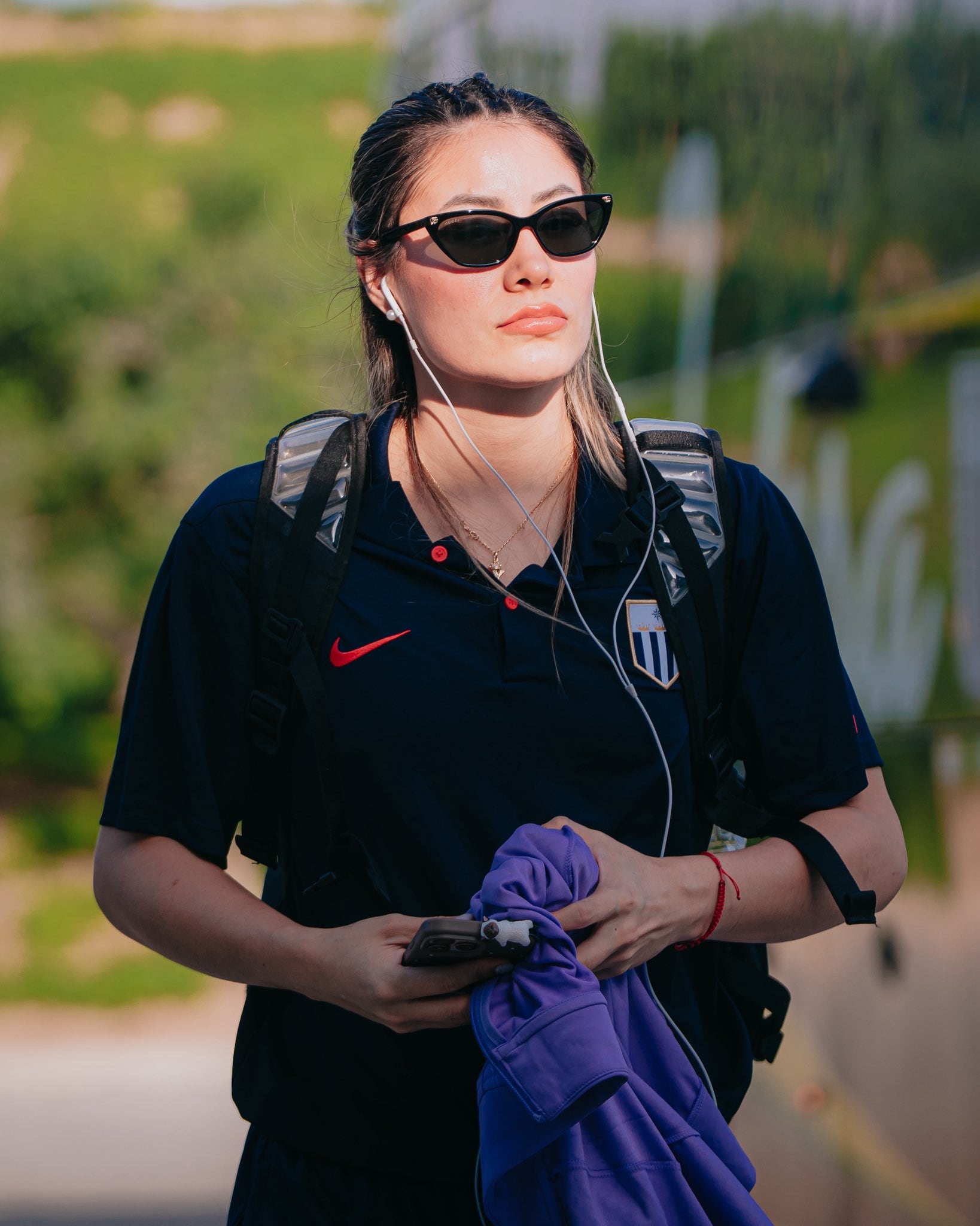 Una integrante del equipo femenino de vóley de Alianza Lima viste la indumentaria oficial del club mientras camina con audífonos y gafas de sol. (@AlianzaLimaVB)
