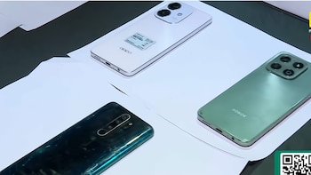 Vista aérea de tres teléfonos celulares de diferentes marcas y colores (uno blanco, uno verde y uno oscuro) colocados sobre hojas de papel blanco