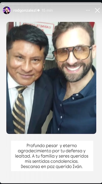 Dos hombres posan sonriendo para una selfie. Uno lleva traje y corbata rayada, el otro una camisa azul oscuro y gafas de sol amarillas