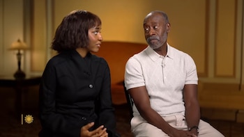 Ayo Edebiri, con cabello oscuro corto y chaqueta negra, mira a Don Cheadle, con barba gris y polo blanco texturizado, sentados en un interior