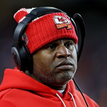 Hombre con barba, gorro de lana rojo con el logotipo de los Kansas City Chiefs, auriculares negros y sudadera roja