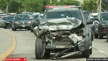 Automóvil gris con la parte frontal destruida detenido en una vía rápida frente a una fila de vehículos detenidos en el tráfico