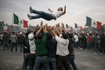 Un grupo de personas levanta y lanza a otra persona en el aire. Hay banderas verdes, blancas y rojas, una multitud y cielo nublado sobre concreto.
