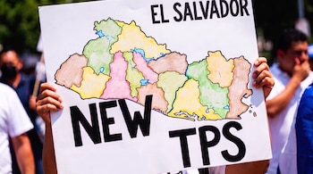 Manos sostienen un cartel blanco con el mapa de El Salvador en colores, el texto "EL SALVADOR" arriba y "NEW TPS" abajo.