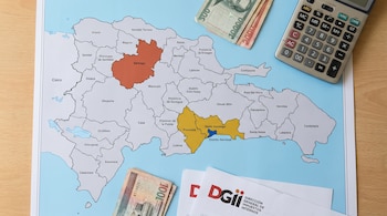 Vista cenital de un mapa físico de República Dominicana con zonas resaltadas, billetes dominicanos, una calculadora y documentos de la DGII.
