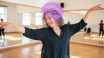 Mujer de mediana edad sonríe en un estudio de danza, con los brazos extendidos. Un contorno de cerebro brillante en morado se superpone a su cabeza.