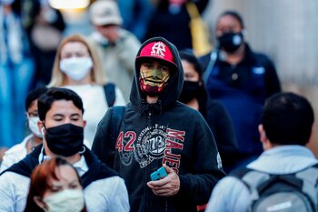 Personas con tapabocas caminan por