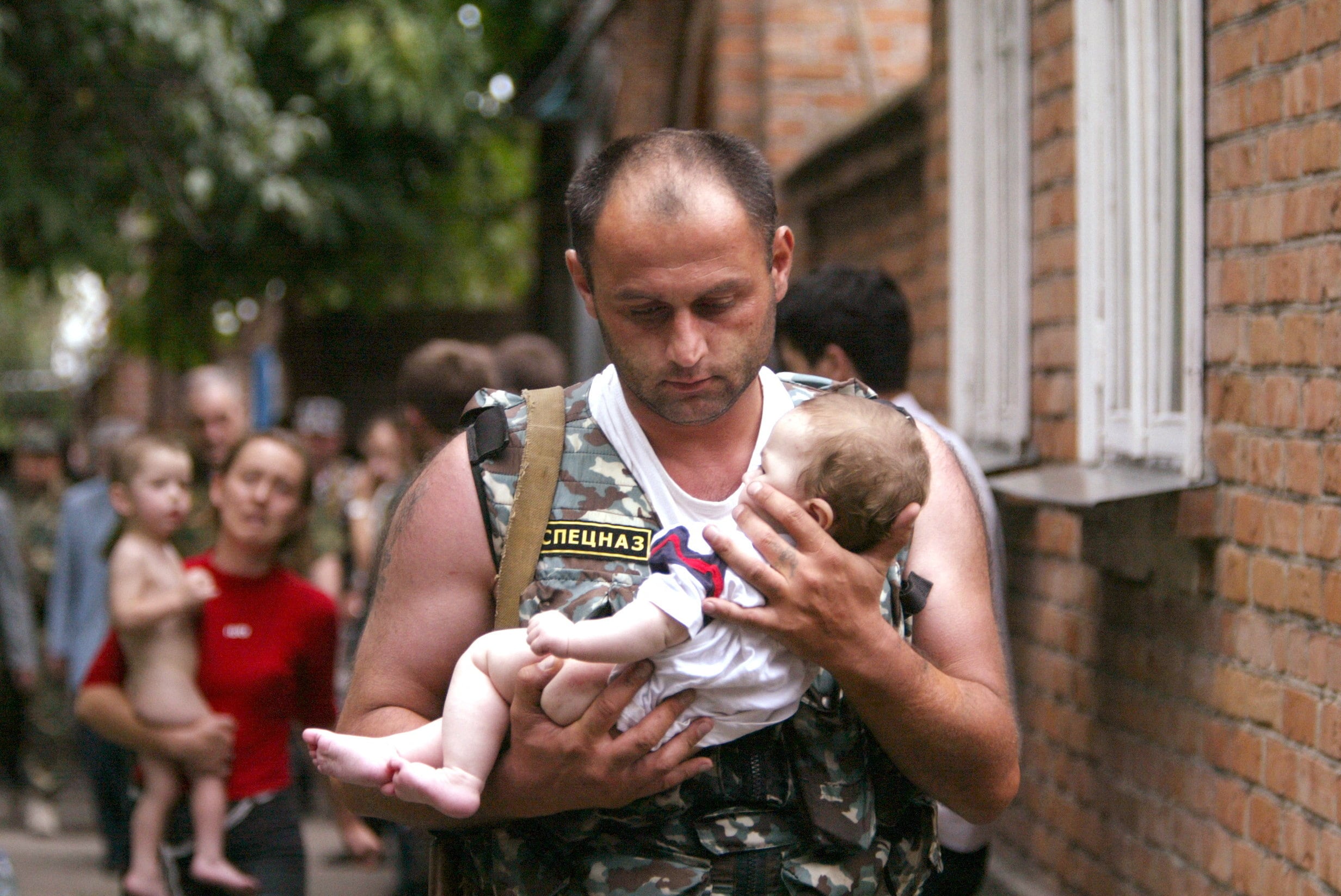 Un integrante de las fuerzas de seguridad rusas carga un bebé rescatado entre los sobrevivientes de la masacre de Beslán (REUTERS/Viktor Korotayev)