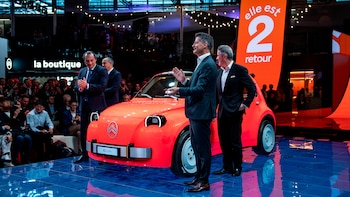 Un automóvil naranja de la marca Citroën en un escenario con tres hombres en traje frente a los asistentes de una exposición
