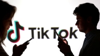 FILE PHOTO: Illustration shows teenagers pose for a photo while holding smartphones in front of a TikTok logo