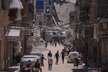 Varios palestinos caminan por una calle rodeada de edificios destruidos por ataques del ejército israelí durante la guerra entre Israel y Hamás en Khan Yunis, en el sur de la Franja de Gaza, el viernes 29 de mayo de 2026 (AP Foto/Abdel Kareem Hana)