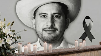 Un retrato en blanco y negro de un hombre con sombrero de vaquero y barba, con velas encendidas, un listón negro de luto y flores blancas en primer plano.