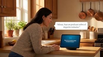 Mujer en una cocina con ventanas, frente a un dispositivo Alexa con pantalla que muestra el texto 'Alexa, haz un podcast sobre el imperio romano'.