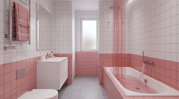 Baño revestido con azulejos blancos y rosas, compuesto por una bañera con cortina translúcida, un lavabo y una ventana al fondo.