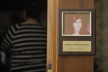 Una placa de madera con un marco dorado contiene la fotografía de una mujer, junto a textos sobre Cristina Siekavizza Molina y Fundación Sobrevivientes