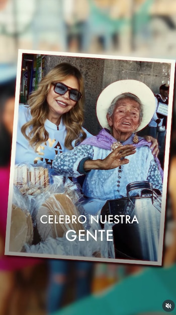 Dos mujeres sonríen a cámara; una con gafas de sol, otra con sombrero. Paquetes de comida, recipiente metálico y calle al fondo