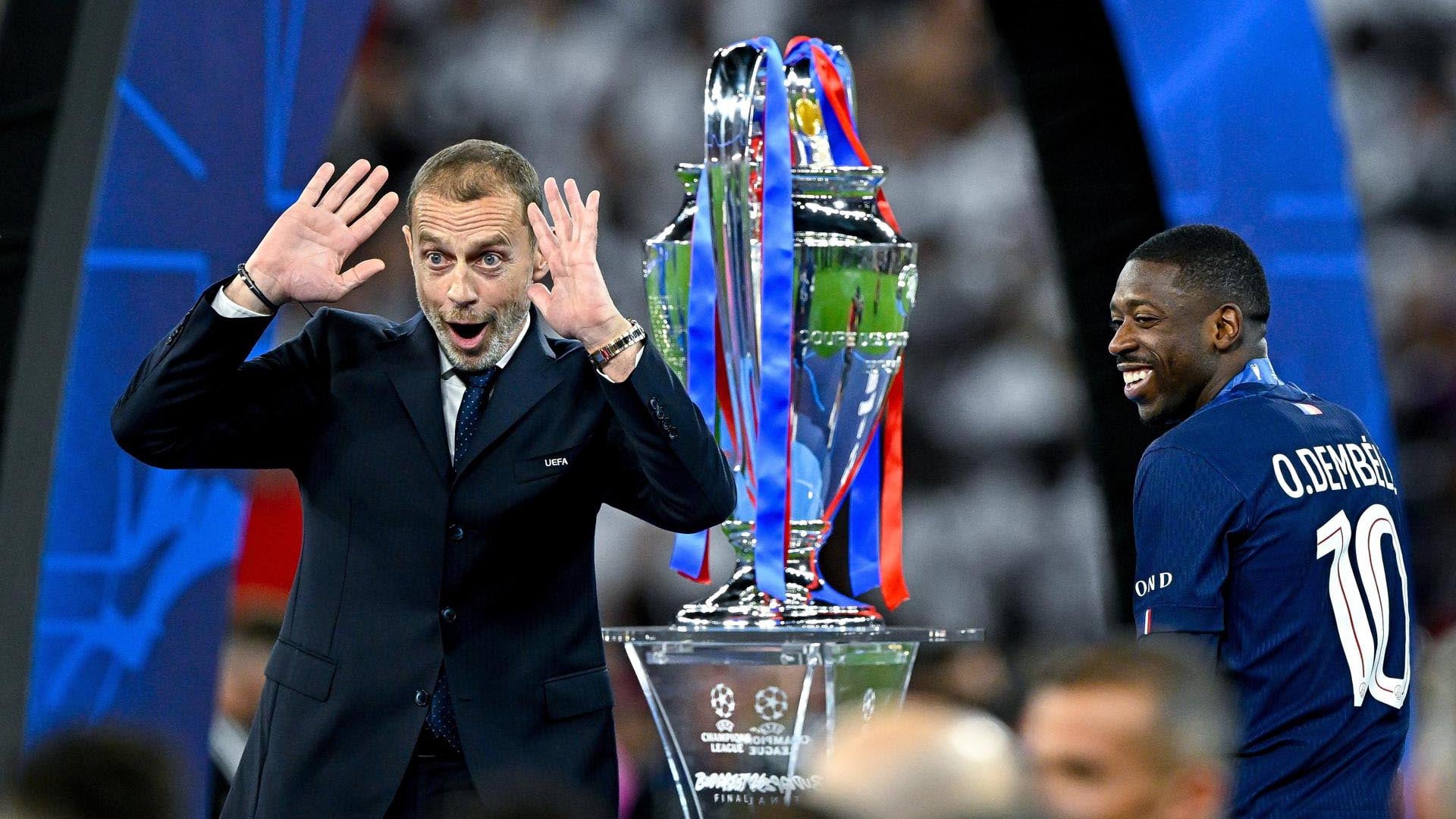 El presidente de la UEFA, Aleksander Čeferin, realiza un gesto de sorpresa junto al trofeo mientras Ousmane Dembélé del PSG sonríe durante la ceremonia de premiación.