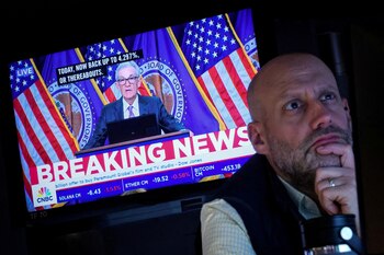 Un operador trabaja, mientras una pantalla retransmite una conferencia de prensa del presidente de la Reserva Federal de Estados Unidos, Jerome Powell (REUTERS/Brendan McDermid)