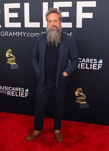 El cantautor Iron & Wine con un conjunto informal compuesto por un traje azul marino y un suéter oscuro debajo. Llevó los pantalones ligeramente remangados, dejando a la vista unos zapatos marrones de cuero desgastado