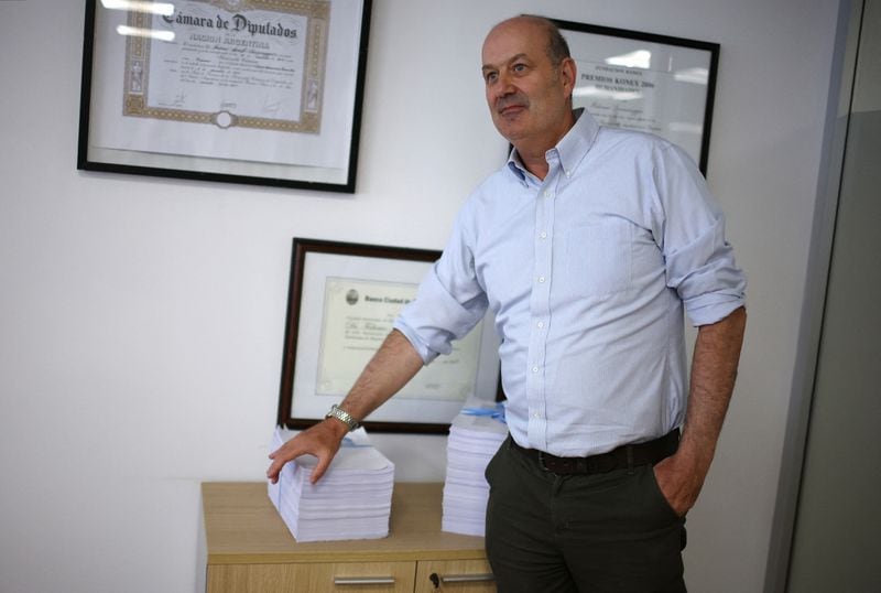 El ministro de Desregulación y Transformación del Estado de Argentina, Federico Sturzenegger, posa junto a un paquete de reformas y nuevas leyes (REUTERS/Agustín Marcarian)