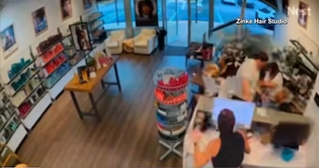 Vista desde una cámara de seguridad del interior de una peluquería con estantes de productos, mostradores y varias personas