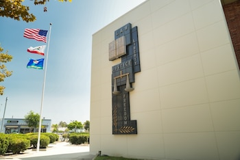 Mástil con banderas de Estados Unidos, California y Los Ángeles. Mural en fachada de edificio con palabras Ley, Justicia, Libertad y una balanza