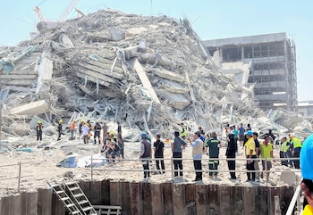 People stand near a collapsed building after a strong earthquake struck central Myanmar on Friday, earthquake monitoring services said, which affected Bangkok as well with hundreds of people pouring out of buildings in the Thai capital in panic after the tremors, in Bangkok, Thailand, March 28, 2025. REUTERS/Ann Wang
