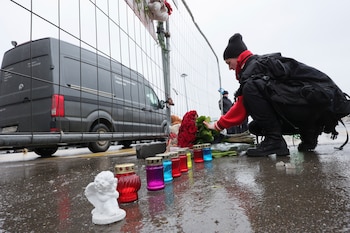 Una mujer deposita flores junto