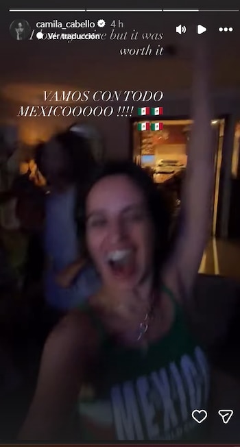 Primer plano de Camila Cabello con la boca abierta y el brazo derecho levantado, vistiendo una camiseta verde, con banderas de México y texto en pantalla